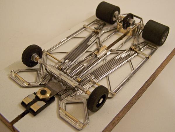 1227-C
Ret-ro rules in-line, all-wire frame (no brass pans); with damper main rails; separate torsional center-guide section built to be as narrow as possible using only four side-by-side pieces of 0.047 wire, attached to motor box via its own damper rails, with torsional flanking wire-pans made of 0.039 wire outer framing wire with 0.032" wire internal structure; separate left-right torsional rails attached to motor box for front axle uprights; torsional inner side pans (0.039 wire outer framing wire with 0.032" wire internal structure) and perimeter wire outer side pans; variable spring-wire tension system between motor box / front-axle uprights for "chassis tuning".